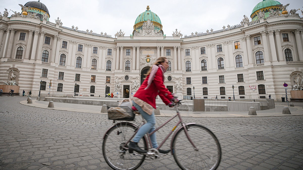 A woman rides a bicycle along an empty street in Vienna, Austria, Monday, Nov. 22, 2021. 