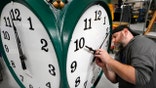 Clock technician Dan LaMoore adjusts clock hands on a large outdoor clock