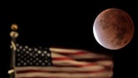 An American flag with the moon in the night sky beyond.