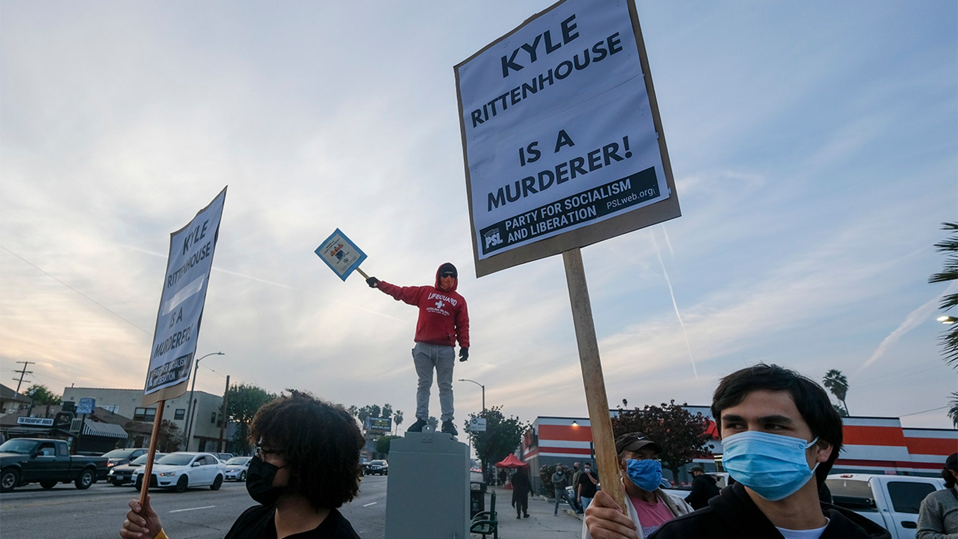 Protesters hold  up a signs, Friday, Nov. 19, 2021, in Los Angeles, following the acquittal of Kyle Rittenhouse in Kenosha, Wis.
