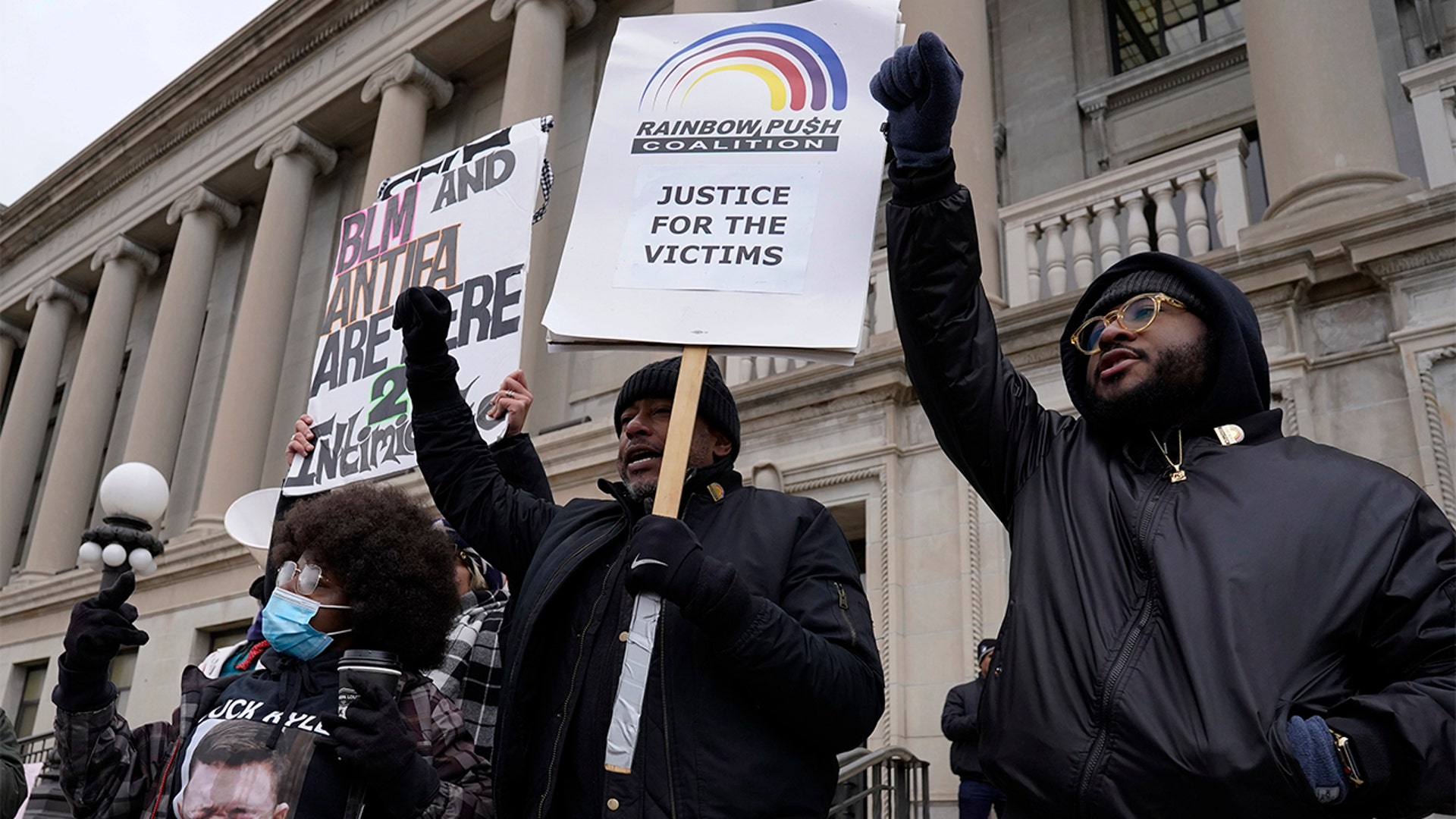 Protesters hold signs outside the Kenosha County Courthouse, Tuesday, Nov. 16, 2021 in Kenosha, Wis., during the Kyle Rittenhouse murder trial. Rittenhouse is accused of killing two people and wounding a third during a protest over police brutality in Kenosha, last year. (AP Photo/Nam Y. Huh)