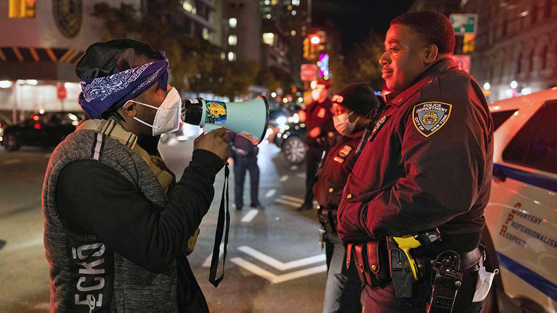 A demonstrator confronts an NYPD officer while marching on the street during a protest against the Kyle Rittenhouse not-guilty verdict near the Barclays Center in New York.