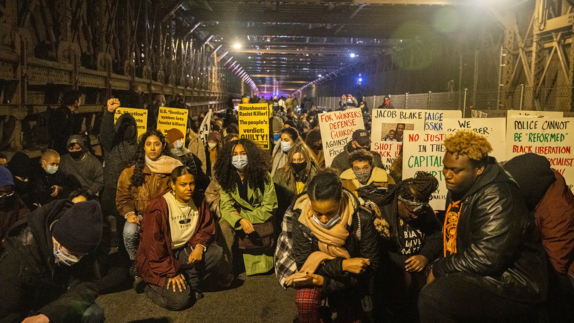 Demonstrators take a knee to have a moment of silence as the march across the Brooklyn Bridge, Friday, Nov. 19, 2021, in New York, following the acquittal of Kyle Rittenhouse in Kenosha, Wis.