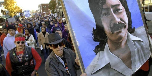   Los manifestantes llevan una pintura grande del indio americano Leonard Peltier encarcelado durante una marcha del Día Nacional de Luto en Plymouth, Massachusetts, el 22 de noviembre de 2001. Exponiendo siglos de racismo y abuso humano Los nativos, tribus nativas americanas de toda Nueva Inglaterra se reunirán el Día de Acción de Gracias 2021 para una celebración solemne del Día Nacional de Luto.