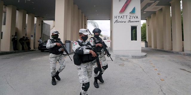 Members of the National Guard walk by the entrance of a hotel after two suspected drug gang members were shot dead in a beachfront clash between rival groups near the Mexican resort of Cancun, in Puerto Morelos, Mexico, Nov. 4, 2021.  