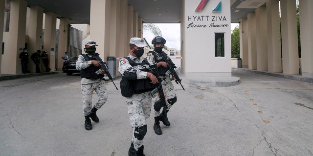 Members of the National Guard walk by the entrance of a hotel after two suspected drug gang members were shot dead in a beachfront clash between rival groups near the Mexican resort of Cancun, in Puerto Morelos, Mexico, Nov. 4, 2021.  