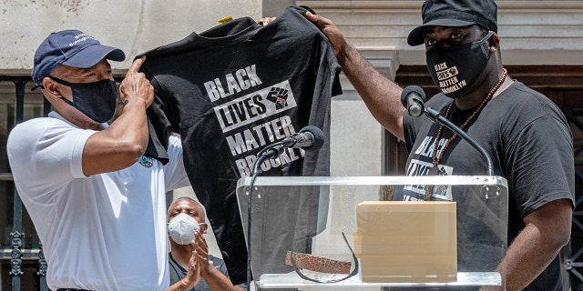 Brooklyn Borough President Eric Adams receives a Black Lives Matter shirt from Anthony Bedford at the opening of the Black Life Matters mural outside Borough Hall in Brooklyn, New York, on June 26, 2020.