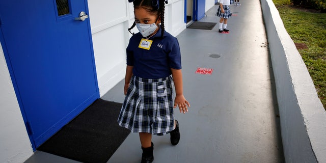 Students wearing a protective mask, queue up outside classrooms on the first day of school, amid the coronavirus disease (COVID-19) pandemic, at St. Lawrence Catholic School in North Miami Beach, Florida, U.S. August 18, 2021. REUTERS/Marco Bello     TPX IMAGES OF THE DAY