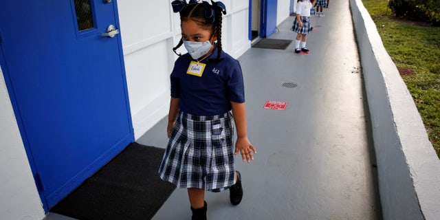Students wearing a protective mask, queue up outside classrooms on the first day of school, amid the coronavirus disease (COVID-19) pandemic, at St. Lawrence Catholic School in North Miami Beach, Florida, U.S. August 18, 2021. REUTERS/Marco Bello TPX IMAGES OF THE DAY