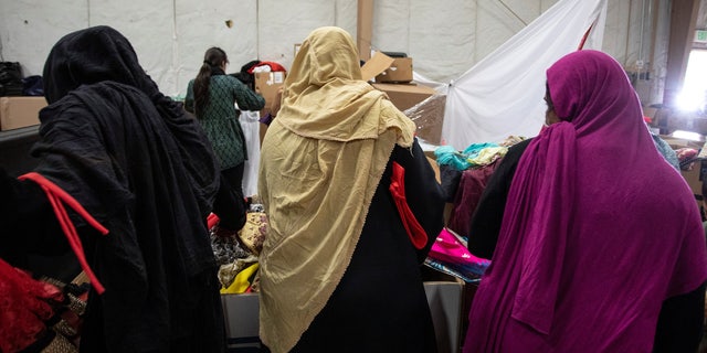Afghan refugees look for donated clothing and shoes at the donation center at Fort McCoy U.S. Army base, 在威斯康星州, 我们。, 九月 30, 2021. Barbara Davidson/Pool via REUTERS