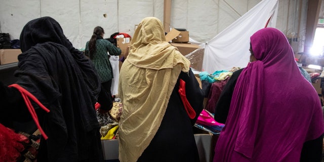Afghan refugees look for donated clothing and shoes at the donation center at Fort McCoy U.S. Army base, in Wisconsin Sept. 30, 2021. (Barbara Davidson/Pool via REUTERS)