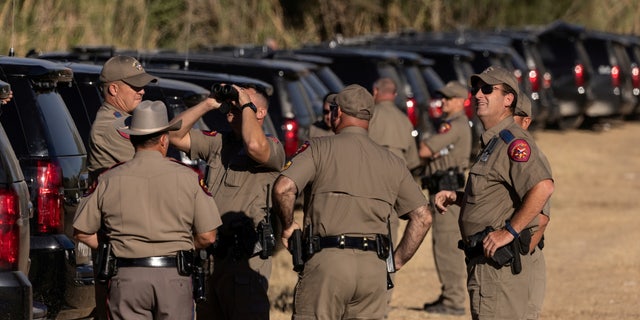 State troopers with the Texas Department of Public Safety look toward a helicopter hovering over a makeshift border camp along the International Bridge in Del Rio, Texas, Sept. 23, 2021.
