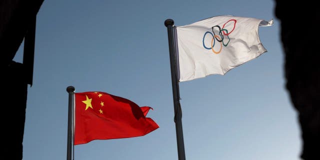 Las banderas china y olímpica ondean en la sede del Comité Organizador de Beijing para los Juegos Olímpicos y Paralímpicos de Invierno 2022 en Beijing, China, el 12 de noviembre de 2021.