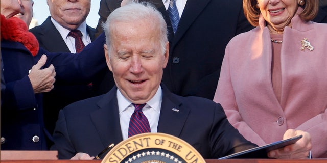 President Biden celebrates with lawmakers, including House Speaker Nancy Pelosi, before signing the Infrastructure Investment and Jobs Act at the White House, Nov. 15, 2021.