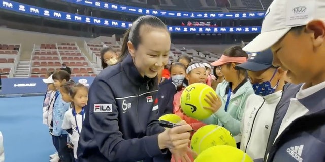 Chinese tennis player Peng Shuai signs large tennis balls at the opening ceremony of Fila Kids Junior Tennis Challenger Final in Beijing, China Nov. 21, 2021, in this screen grab obtained from a social media video.
