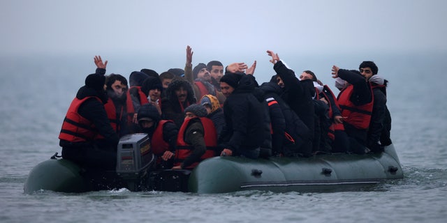 A group of more than 40 migrants react as they succeeded to get on an inflatable dinghy, to leave the coast of northern France and to cross the English Channel, near Wimereux, France, November 24, 2021. REUTERS/Gonzalo Fuentes