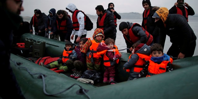 A group of more than 40 migrants with children get on an inflatable dinghy, as they leave the coast of northern France to cross the English Channel, near Wimereux, France, Nov. 24, 2021.