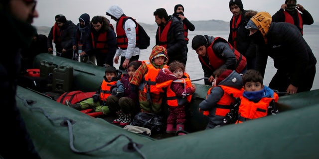 A group of more than 40 migrants with children get on an inflatable dinghy, as they leave the coast of northern France to cross the English Channel, near Wimereux, France, Nov. 24, 2021. 