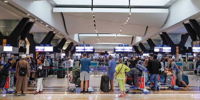 Travelers queue at a check-in counter at OR Tambo International Airport in Johannesburg, South America, on Nov. 27, 2021, after several countries banned flights from South Africa following the discovery of a new COVID-19 variant omicron. (Photo by PHILL MAGAKOE/AFP via Getty Images)