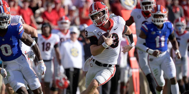 Georgia quarterback Stetson Bennett (13) scrambles for yardage in front of Florida safety Trey Dean III (0) and linebacker Mohamoud Diabate (11) during the first half Oct. 30, 2021, in Jacksonville, Fla.