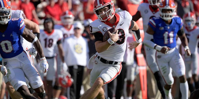 Georgia quarterback Stetson Bennett (13) scrambles for yardage in front of Florida safety Trey Dean III (0) and linebacker Mohamoud Diabate (11) during the first half Oct. 30, 2021, in Jacksonville, Fla.