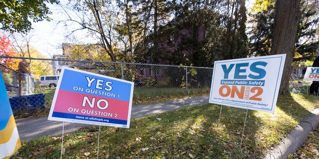 Lawn signs are in conflict with each other outside a polling station Tuesday in Minneapolis.  (AP Photo / Christian Monterrosa)