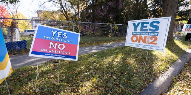 Lawn signs are in conflict with each other outside a polling station Tuesday in Minneapolis. (AP Photo / Christian Monterrosa)