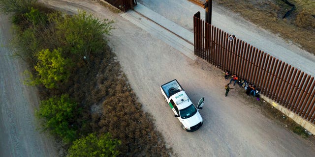 FILE - A Border Patrol agent talks to migrants after they were detained and taken into custody, March 21, 2021, in Abram-Perezville, Texas. Biden took office on Jan. 20 and almost immediately, numbers of migrants exceeded expectations. (AP Photo/Julio Cortez, File)