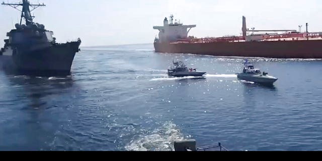 This frame grab from a video released by Iran's paramilitary Revolutionary Guard on Wednesday, Nov. 3, 2021, shows the Guard speed boats, center, in front of a U.S warship, left, amid the seizure of a Vietnamese-flagged oil tanker, right, in the Gulf of Oman. Iran seized the tanker in the Gulf of Oman last month and still holds the vessel, two U.S. officials told The Associated Press on Wednesday, revealing the latest provocation in Mideast waters as tensions escalate between Iran and the United States over Tehran's nuclear program. (Revolutionary Guard via AP)