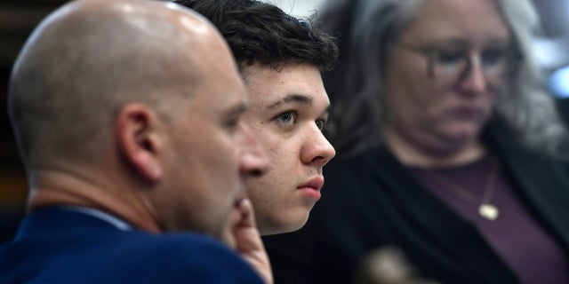 Kyle Rittenhouse, center, looks up and away from a video monitor as footage of him shooting on the night of Aug. 25, 2020, is shown during the trial at the Kenosha County Courthouse in Kenosha, Wisconsin, on Wednesday, Nov. 3 2021.