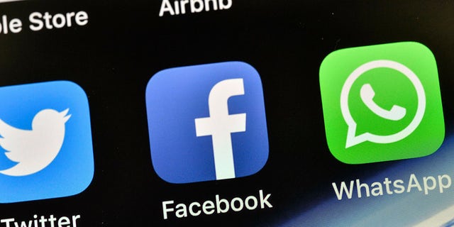 The icons of Facebook and WhatsApp are seen on an iPhone.