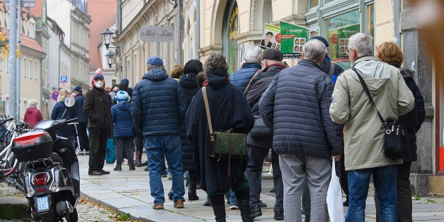 Les gens font la queue pour se faire vacciner contre le coronavirus lors d'une campagne de vaccination de la DRK, la Croix-Rouge allemande, devant la mairie de Pirna, en Allemagne, le lundi 15 novembre 2021. (Robert Michael/dpa via AP )