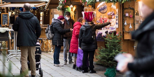 People wearing face mask to protect against the coronavirus as they visits a Christmas market in Vienna, Austria, Wednesday, Nov. 17, 2021. The Austrian a nationwide lockdown for unvaccinated people is in place to combat rising coronavirus infections and deaths. (AP Photo/Michael Gruber)
