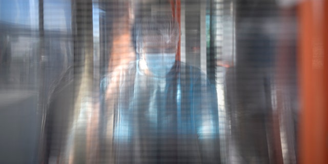 FILE - A medical worker is seen through a plastic panel in a bus that will serve as a mobile COVID-19 vaccination unit in Bucharest, Romania, Saturday, Sept. 4, 2021. (AP Photo/Andreea Alexandru, File)