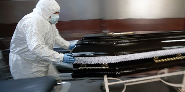 FILE - Funeral house employees drag a coffin on a trolley as they arrive at the University Emergency Hospital morgue to take a COVID-19 victim for burial, in Bucharest, Romania, Monday, Nov. 8, 2021. (AP Photo/Vadim Ghirda, File)