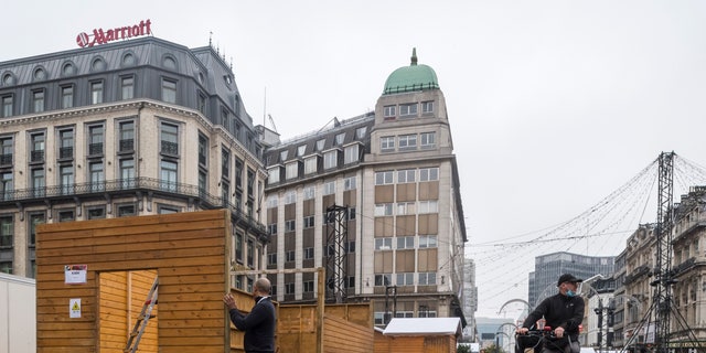 A man works on stalls for the Christmas Market in Brussels, Friday Nov. 19, 2021. In Brussels a 60-foot Christmas tree was placed in the center of the city's stunning Grand Place on Thursday Nov. 18 but a decision on whether the Belgian capital's festive market can go ahead will depend on the development of the COVID-19 virus surge. (AP Photo/Geert Vanden Wijngaert)