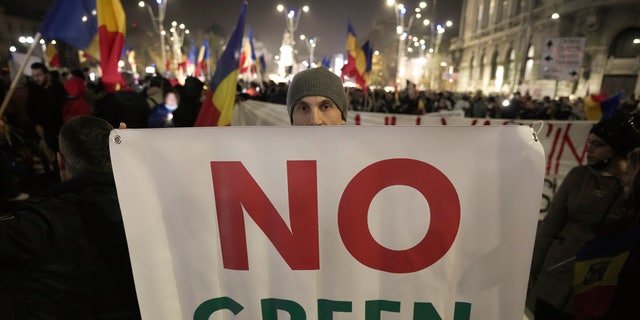 FILE - A man holds a banner during a protest against vaccinations, the introduction of the green pass and COVID-19 related restrictions in Bucharest, Romania, Sunday, Nov. 7, 2021. This was supposed to be the Christmas in Europe where family and friends could once again embrace holiday festivities and one another. Instead, the continent is the global epicenter of the COVID-19 pandemic as cases soar to record levels in many countries. With infections spiking again despite nearly two years of restrictions, the health crisis increasingly is pitting citizen against citizen — the vaccinated against the unvaccinated. (AP Photo/Vadim Ghirda, File)