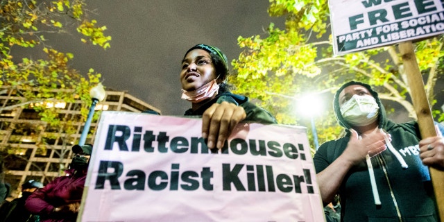 Bria Swenson holds a sign Friday, Nov. 19, 2021, in Oakland, Calif., following the acquittal of Kyle Rittenhouse in Kenosha, Wis. Asserting self-defense, Rittenhouse was acquitted of all charges Friday in the deadly shootings that became a flashpoint in the debate over guns, vigilantism and racial injustice in the United States. (AP Photo/Noah Berger)