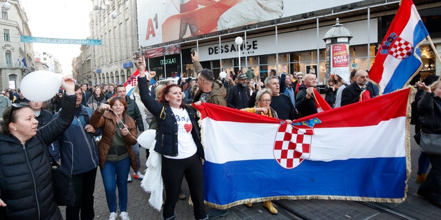 People march down a street during a protest against vaccination and coronavirus measures in Zagreb, Croatia, Saturday, Nov. 20, 2021. Thousands of protesters gathered in Zagreb on Saturday after earlier this month the authorities introduced more restrictive measures to fight the surge of coronavirus infections in the country. (AP Photo)
