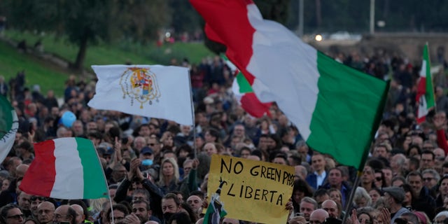 A demonstrator holds a banner reading "No Green Pass, freedom" during a protest agaist restrictions for the unvaccinated at Rome Circus Maximus, Saturday, Nov. 20, 2021. With infections spiking again despite nearly two years of restrictions, the health crisis increasingly is pitting citizen against citizen — the vaccinated against the unvaccinated. (AP Photo/Alessandra Tarantino)