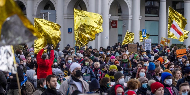 A few hundred people with banners and gold-and-silver hypothermia blankets march in Warsaw, Poland, on Saturday, Nov. 20, 2021, in support of the migrants stranded at the Belarus-Poland border. (AP Photo)