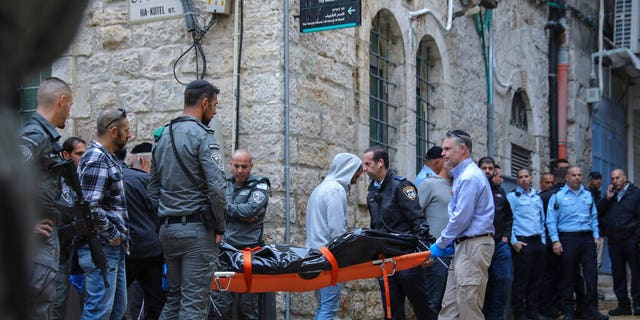 Israeli security personnel and members of Zaka Rescue and Recovery team carry the body of a Palestinian man who was fatally shot by Israeli police after he killed one Israeli and wounded four others in a shooting attack in Jerusalem's Old City, Sunday, Nov. 21, 2021. (AP Photo/Mahmoud Illean)