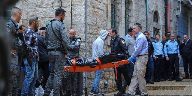 Israeli security personnel and members of Zaka Rescue and Recovery team carry the body of a Palestinian man who was fatally shot by Israeli police after he killed one Israeli and wounded four others in a shooting attack in Jerusalem's Old City, Sunday, Nov. 21, 2021. (AP Photo/Mahmoud Illean)