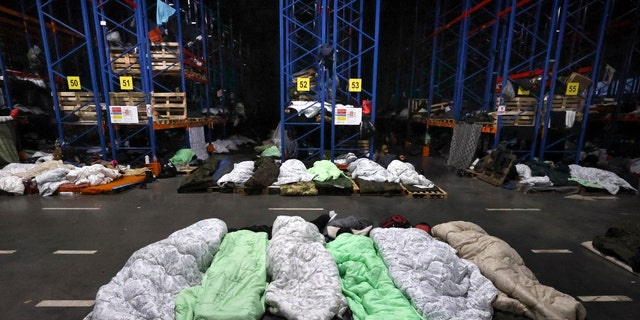 Migrants sleep in a logistics center at the checkpoint "Kuznitsa" at the Belarus-Poland border near Grodno, Belarus, Sunday, Nov. 21, 2021. The EU says the new surge of migrants on its eastern borders has been orchestrated by the leader of Belarus, President Alexander Lukashenko, in retaliation for EU sanctions placed on Belarus after a government crackdown on peaceful democracy protesters. It calls the move "a hybrid attack'' on the bloc. Belarus denies the charge. (Maxim Guchek/BelTA via AP)