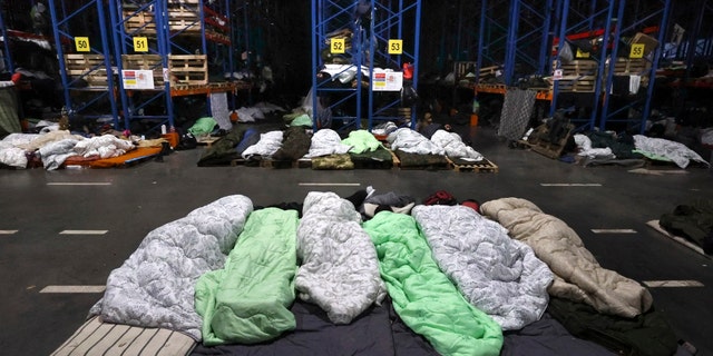 Migrants sleep in a logistics center at the checkpoint "Kuznitsa" at the Belarus-Poland border near Grodno, Belarus, Sunday, Nov. 21, 2021. The EU says the new surge of migrants on its eastern borders has been orchestrated by the leader of Belarus, President Alexander Lukashenko, in retaliation for EU sanctions placed on Belarus after a government crackdown on peaceful democracy protesters. It calls the move "a hybrid attack'' on the bloc. Belarus denies the charge. (Maxim Guchek/BelTA via AP)