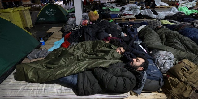 Migrants sleep inside a logistics center at the checkpoint "Kuznitsa" at the Belarus-Poland border near Grodno, Belarus, Sunday, Nov. 21, 2021. The EU says the new surge of migrants on its eastern borders has been orchestrated by the leader of Belarus, President Alexander Lukashenko, in retaliation for EU sanctions placed on Belarus after a government crackdown on peaceful democracy protesters. It calls the move "a hybrid attack'' on the bloc. Belarus denies the charge. (Maxim Guchek/BelTA via AP)