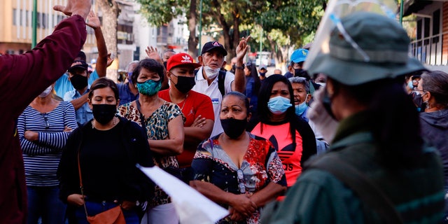 People argue with election officials at a polling station that did not open on time, during regional elections, in the San Agustin neighborhood of Caracas, Venezuela, Sunday, Nov. 21, 2021. Venezuelans go to the polls to elect state governors and other local officials. (AP Photo/Jesus Vargas)