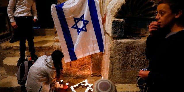 Israeli youth light candles in the shape of the Star of David at the site of a shooting attack that killed an Israeli man in Jerusalem's Old City, Sunday, Nov. 21, 2021. (AP Photo/Ariel Schalit)