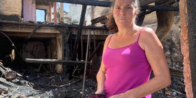 Emilie holds her burned passport in her charred home following riots in Pointe-a-Pitre, Guadeloupe island, Sunday, Nov.21, 2021. French authorities are sending police special forces to the Caribbean island of Guadeloupe, an overseas territory of France, as protests over COVID-19 restrictions erupted into rioting. In Pointe-a-Pitre, the island's largest urban area, clashes left three people injured, including a 80-year-old woman who was hit by a bullet while on her balcony. A firefighter and a police officer were also injured and several shops were looted there and in other towns. (AP Photo/Elodie Soupama)