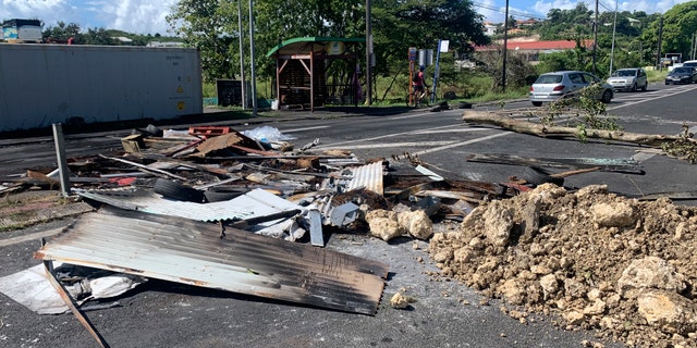 Des débris laissés par des manifestants bloquent une rue du Gosier, île de Guadeloupe, dimanche 21 novembre 2021. Les autorités françaises ont envoyé des forces spéciales de police sur l'île caribéenne de Guadeloupe, un territoire français d'outre-mer, alors que des manifestations contre les restrictions du COVID-19 éclataient en émeutes et pillages pour le troisième jour consécutif. Dimanche, de nombreux barrages routiers par des manifestants ont rendu les déplacements à travers l'île presque impossibles. (AP Photo/Élodie Soupama)
